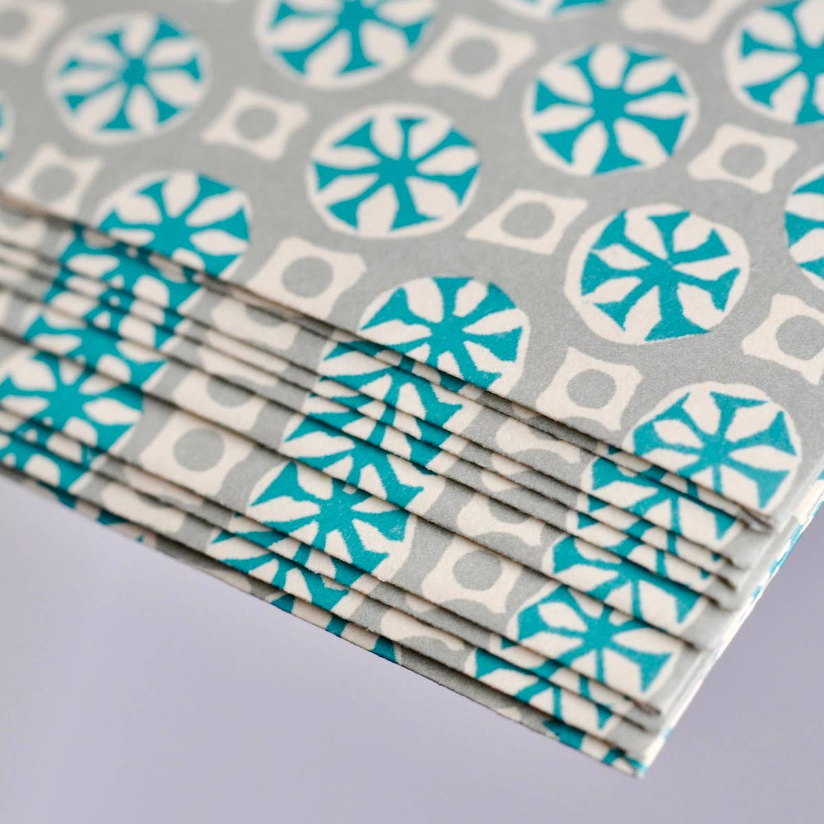 Stack of paper napkins with blue and white geometric pattern on gray background