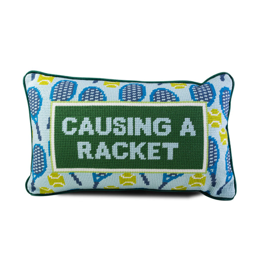 Decorative pillow with tennis racket pattern and 'Causing a Racket' text on a white background