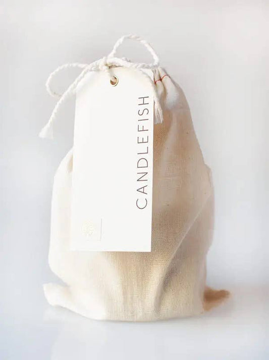Beige drawstring bag with 'Candlefish' candle