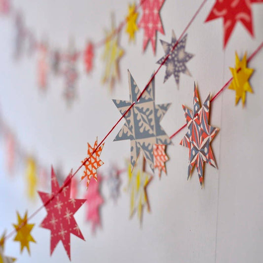 String of colorful star-shaped paper decorations on a white background
