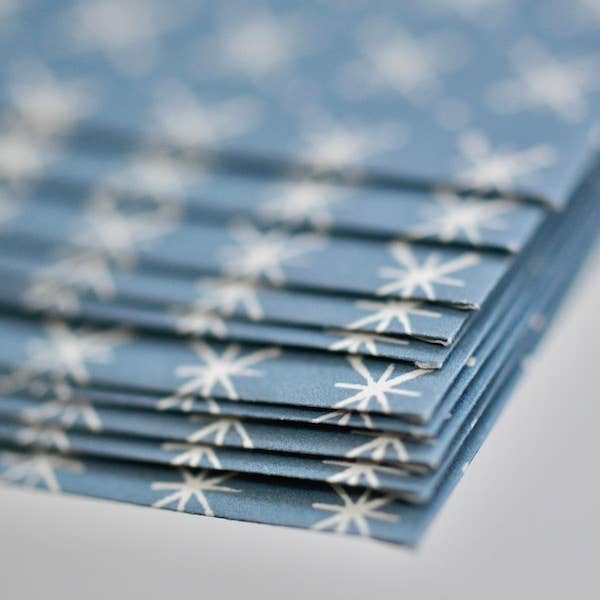 Stack of blue napkins with white star patterns on a light gray surface