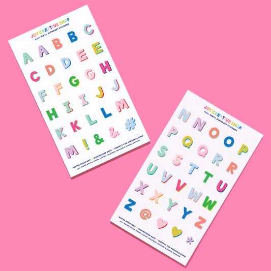 Two sheets of colorful alphabet stickers on a pink background