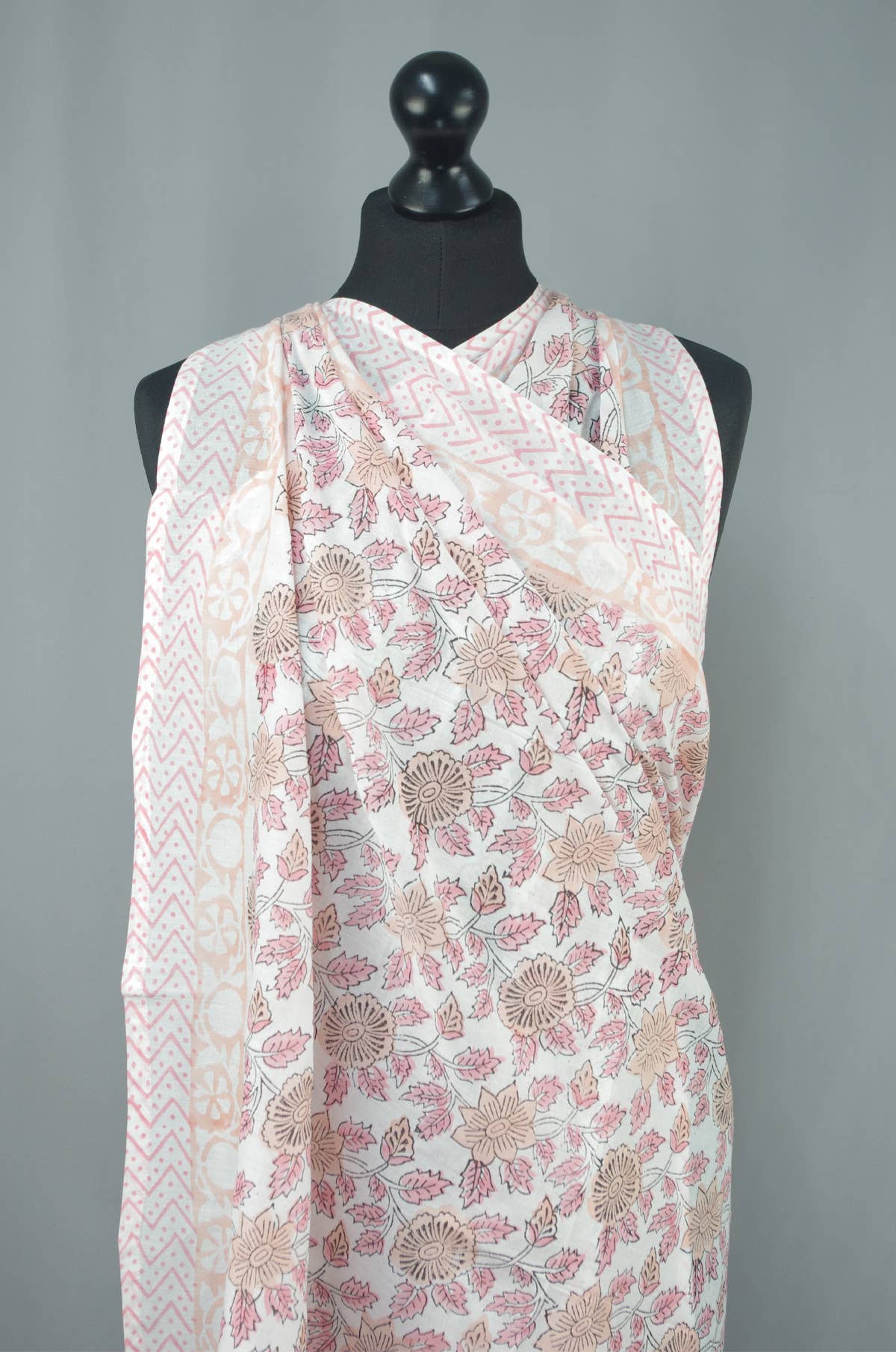 Floral patterned scarf draped over a mannequin against a gray background