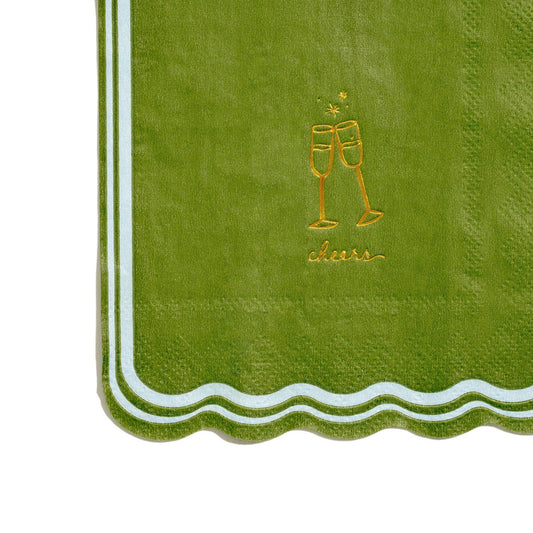 Green napkin with gold 'cheers' and champagne glass design on a white background