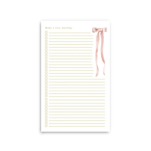 Notepad with gold text and a pink ribbon on a white background