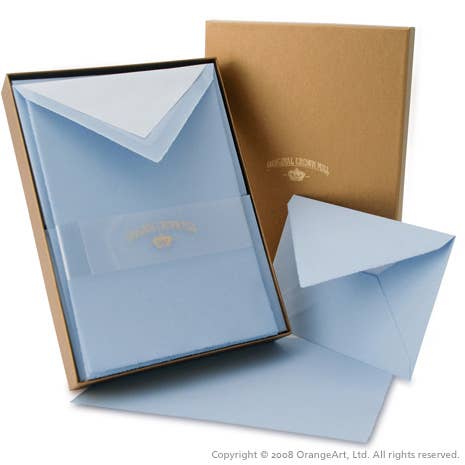 Open brown box with a clear lid revealing light blue paper inside, featuring a logo.