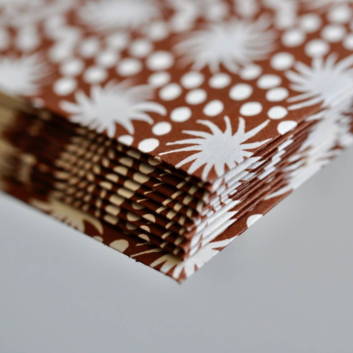 Stack of brown paper with white floral patterns on a gray surface