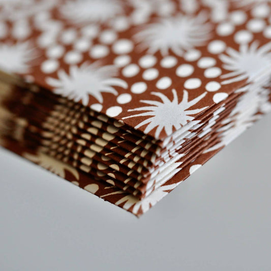 Stack of brown paper with white floral patterns on a gray surface