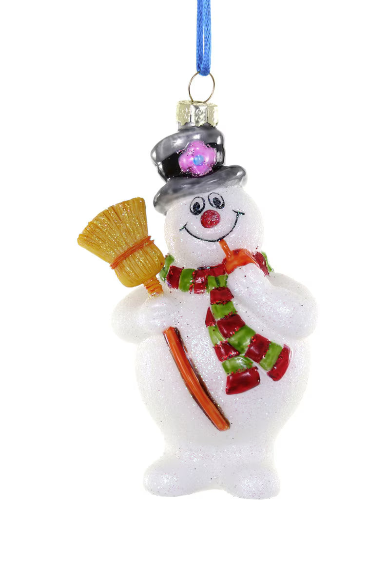 A white glittery snowman Christmas ornament holding a yellow broom and orange stick, wearing a gray top hat with a pink gem and a red and green striped scarf, hanging from a blue ribbon.