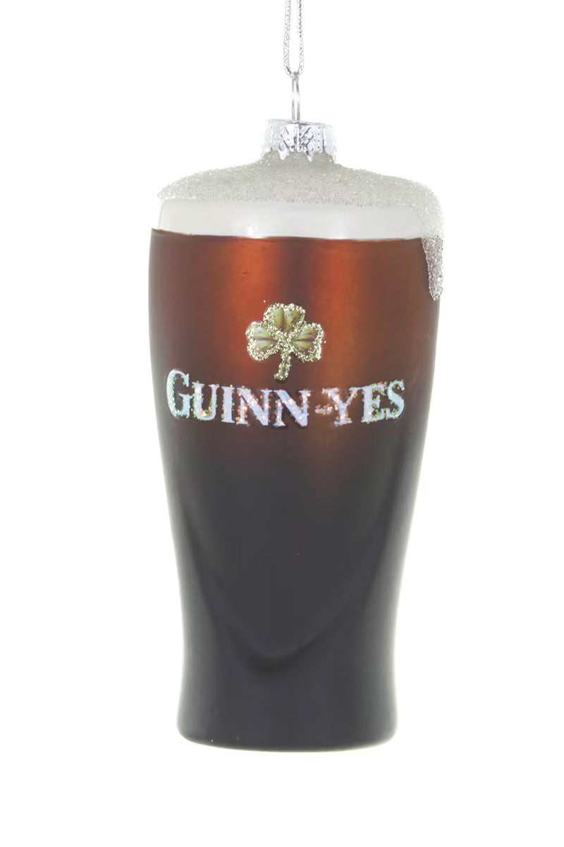 A Guinness-themed hanging ornament shaped like a pint glass filled with dark stout and white foam, featuring a glittery shamrock and the words 'GUINNESS' on the front, shown against a plain white background.