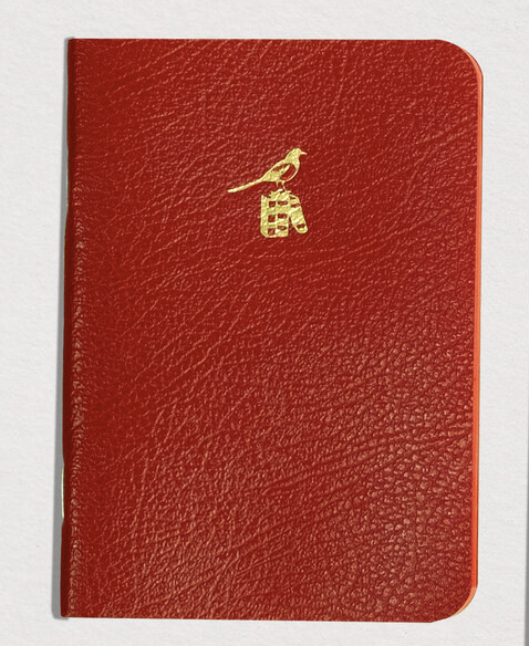 Red notebook with a gold emblem on a white background