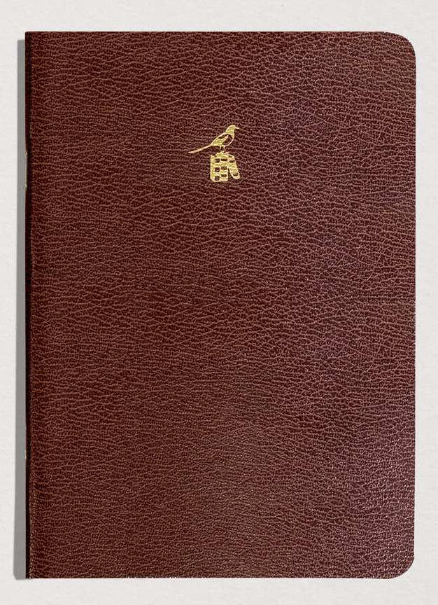 Brown leather notebook with a gold emblem on a light gray background