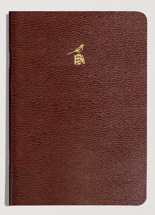 Brown leather notebook with a gold emblem on a light gray background