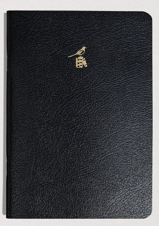 Black leather notebook with a gold emblem on a white background