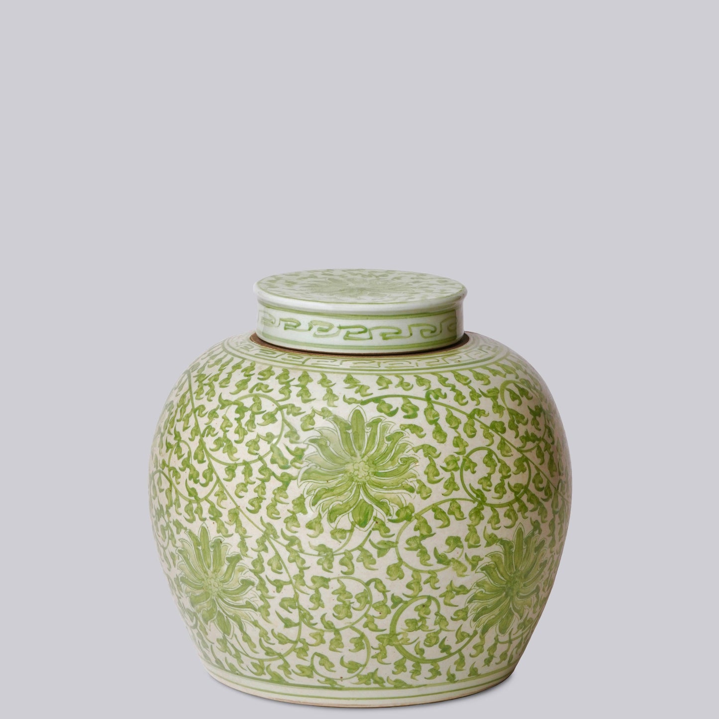 Green and white ceramic jar with intricate patterns on a light gray background