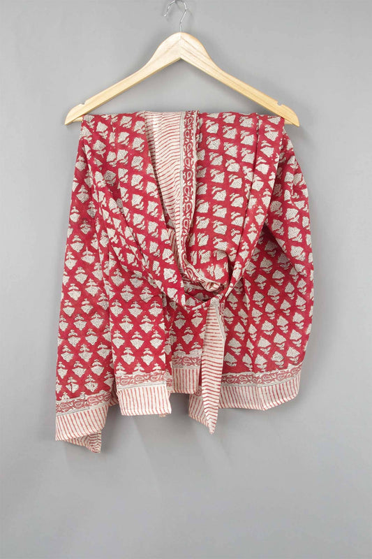Red and white patterned garment on a hanger against a gray background