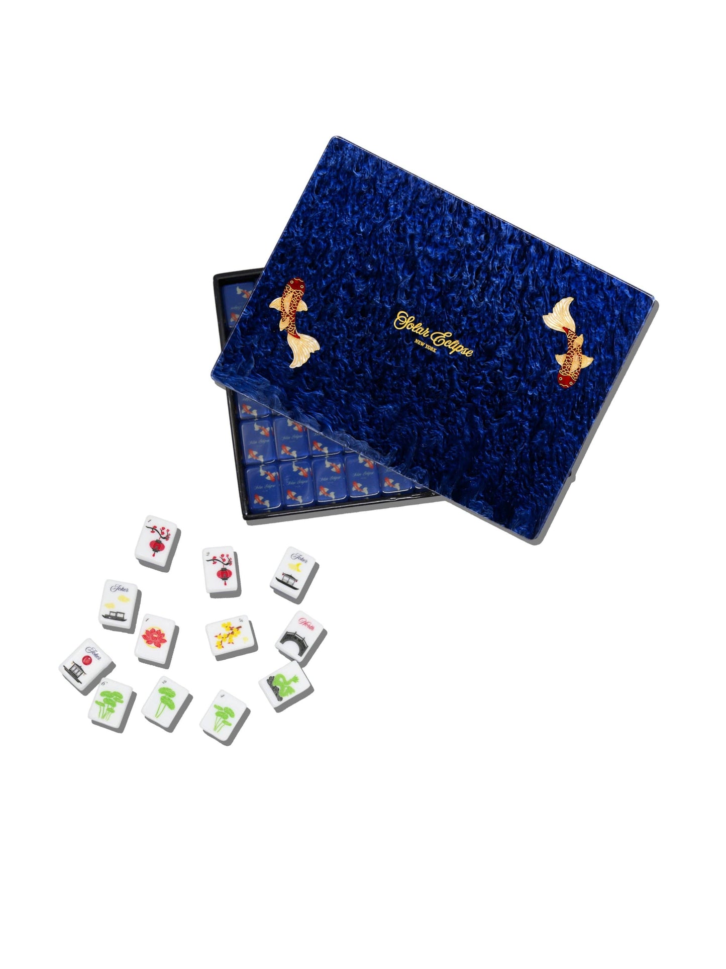 A mahjong set with a dark blue velvet case, shown open with several tiles scattered in front on a white background. The case features gold foil koi fish designs and the brand name 'Blue Dragon' in gold script.