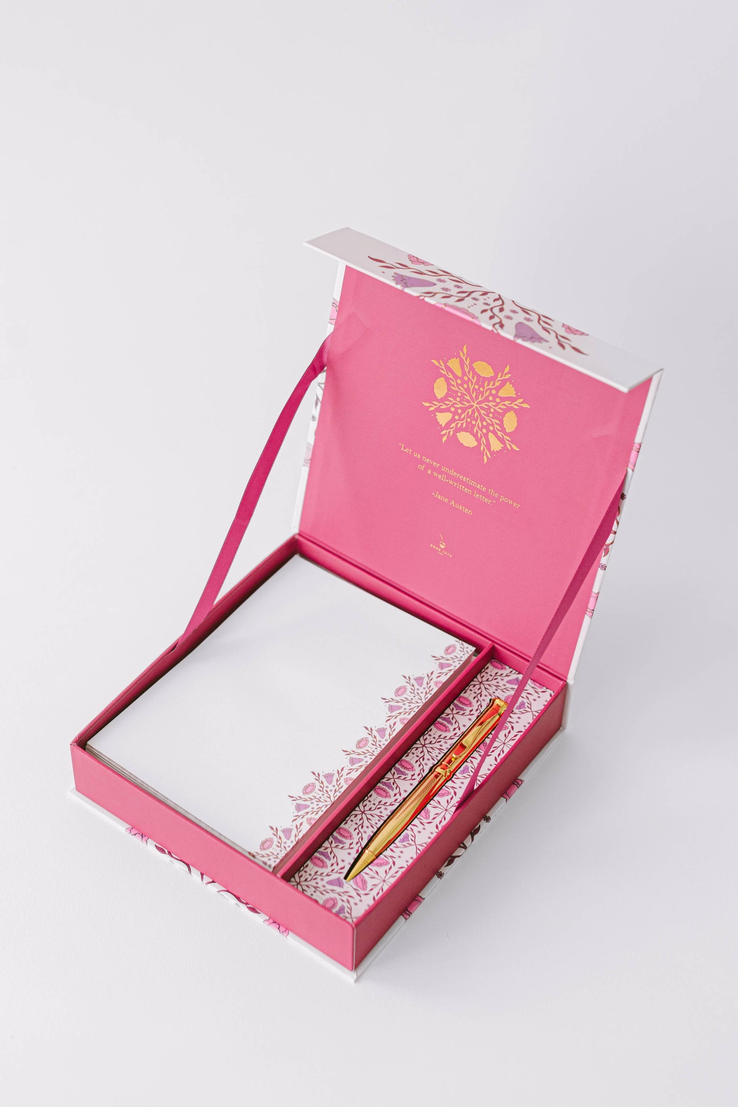 Pink stationery set with a notebook and pen in an open box on a white background