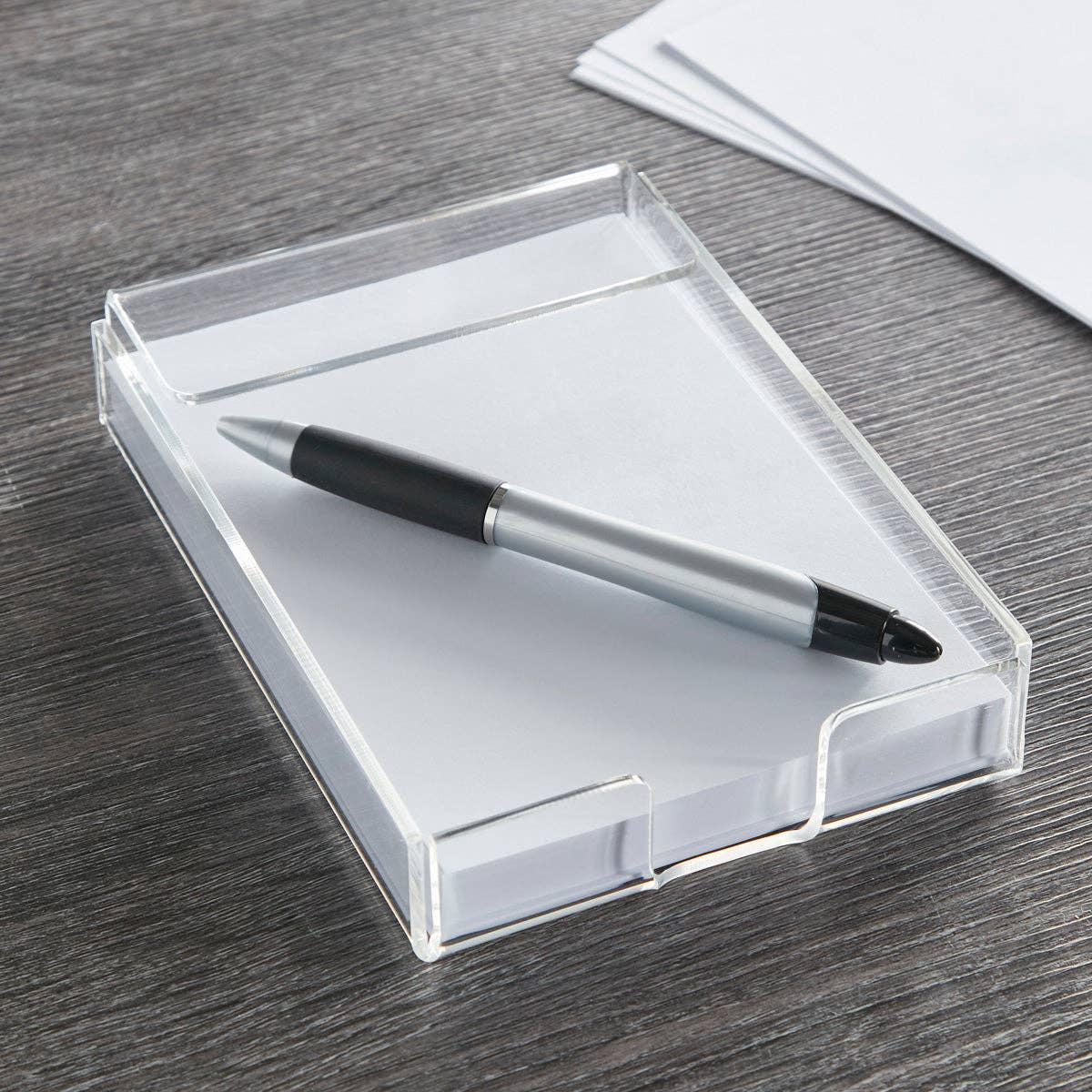 Clear acrylic desk organizer with a pen on a wooden surface