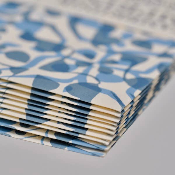 Stack of blue and white patterned envelopes on a gray surface