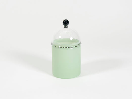 A light mint green glass jar with a clear glass dome lid featuring a black spherical finial and a decorative silver-colored beaded band.