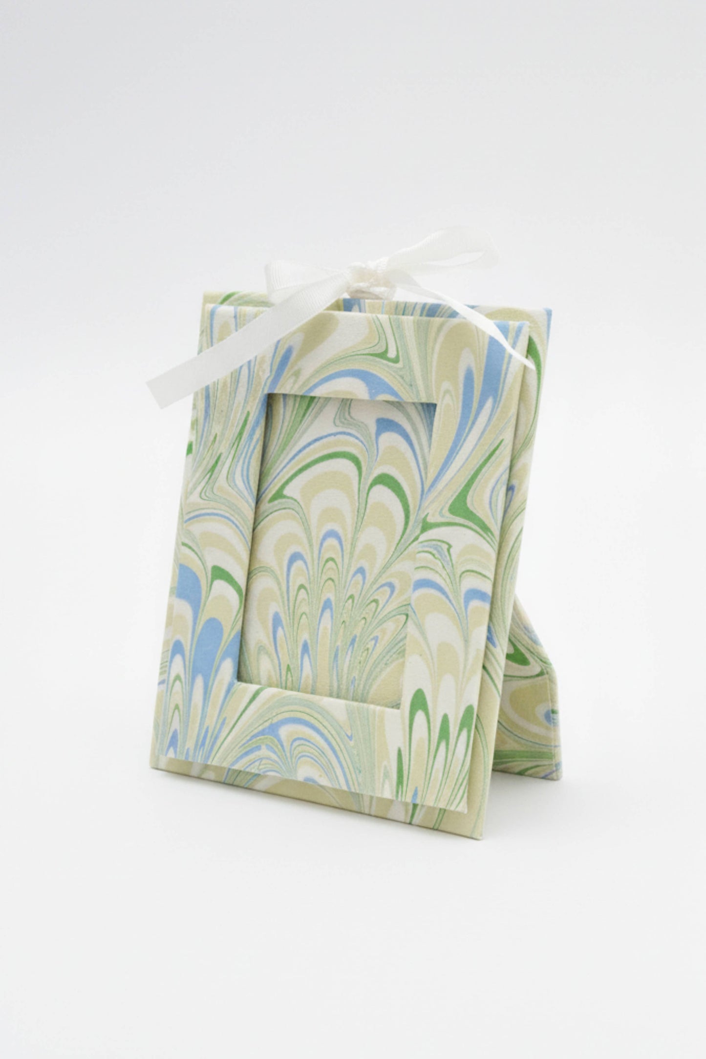 Marbled green and blue gift box with a white ribbon on a white background