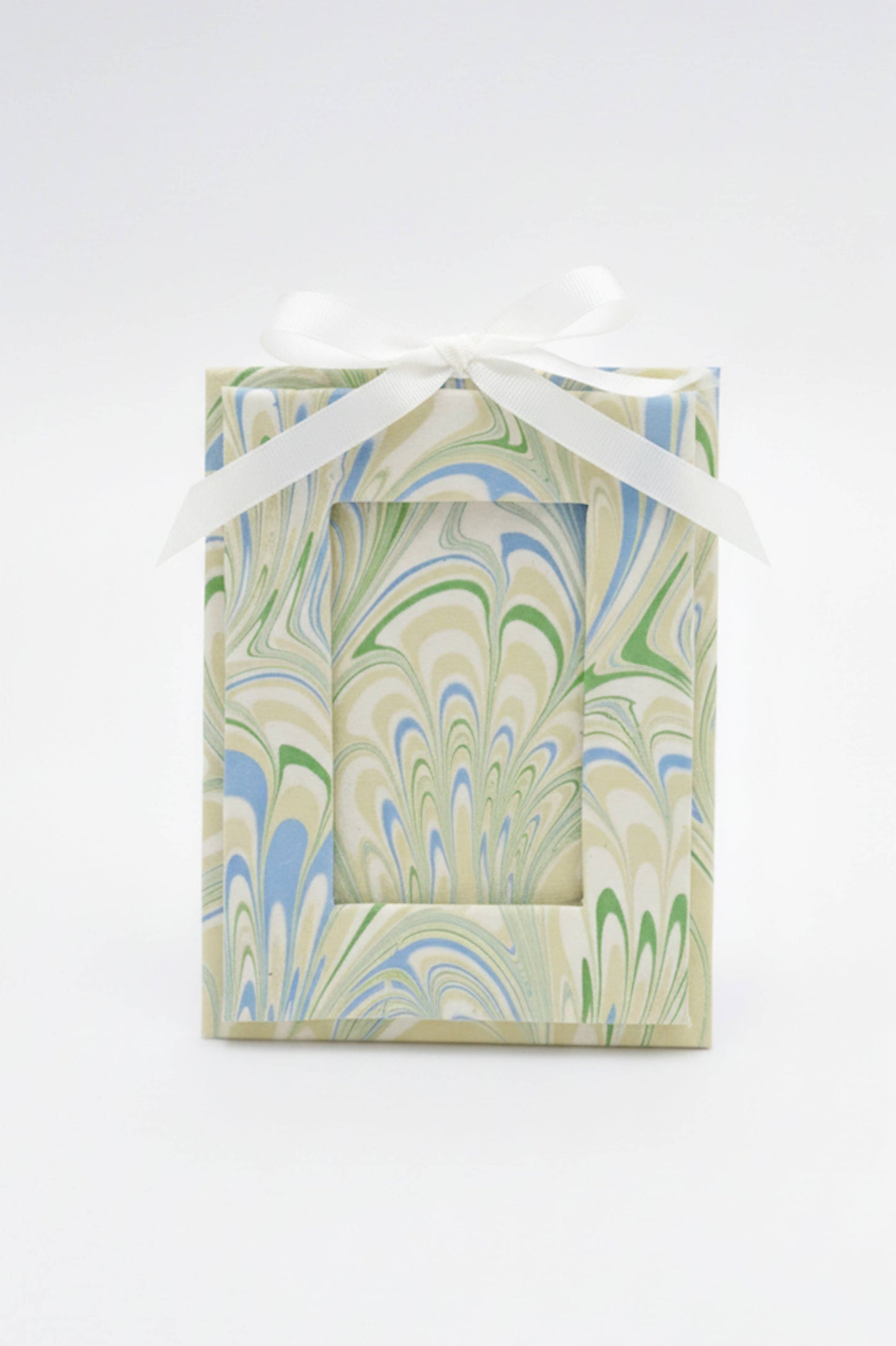 Gift box with marbled pattern and white ribbon on a white background