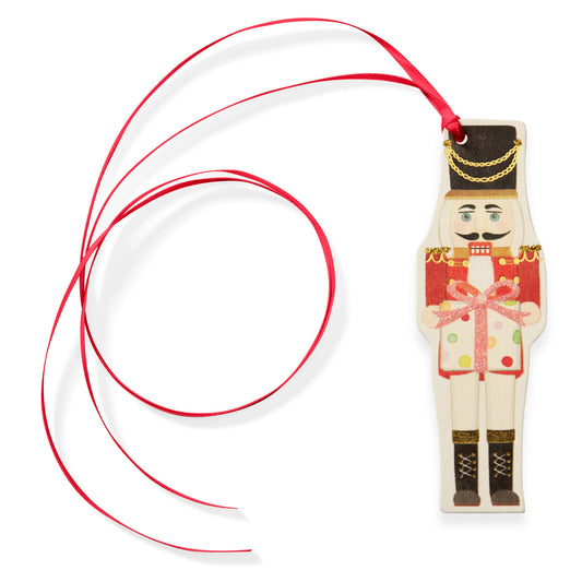 nutcracker tag ornament with a red ribbon on a white background