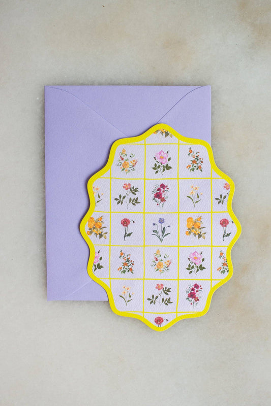 Floral card with a yellow border on a purple envelope against a beige background