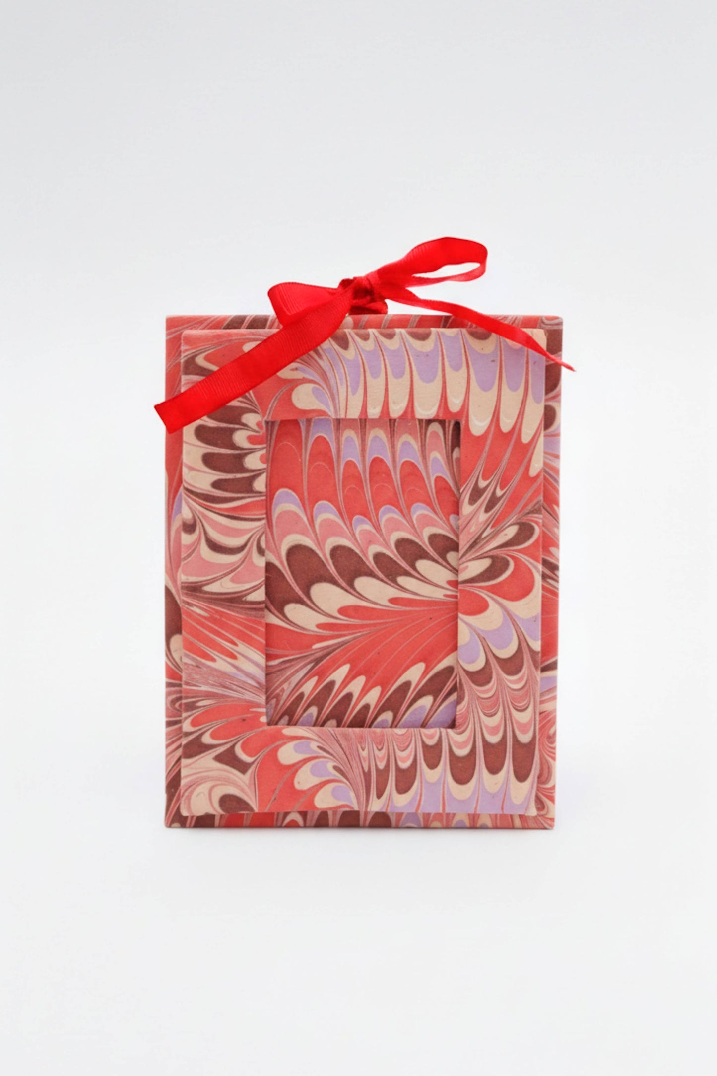 Gift box with marbled design and red ribbon on a white background