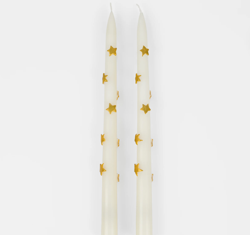 A set of two taper candles with a gold star design, displayed against a white background.